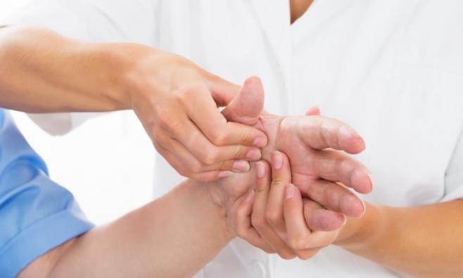 Physiotherapeutin behandelt linke Hand einer Patientin